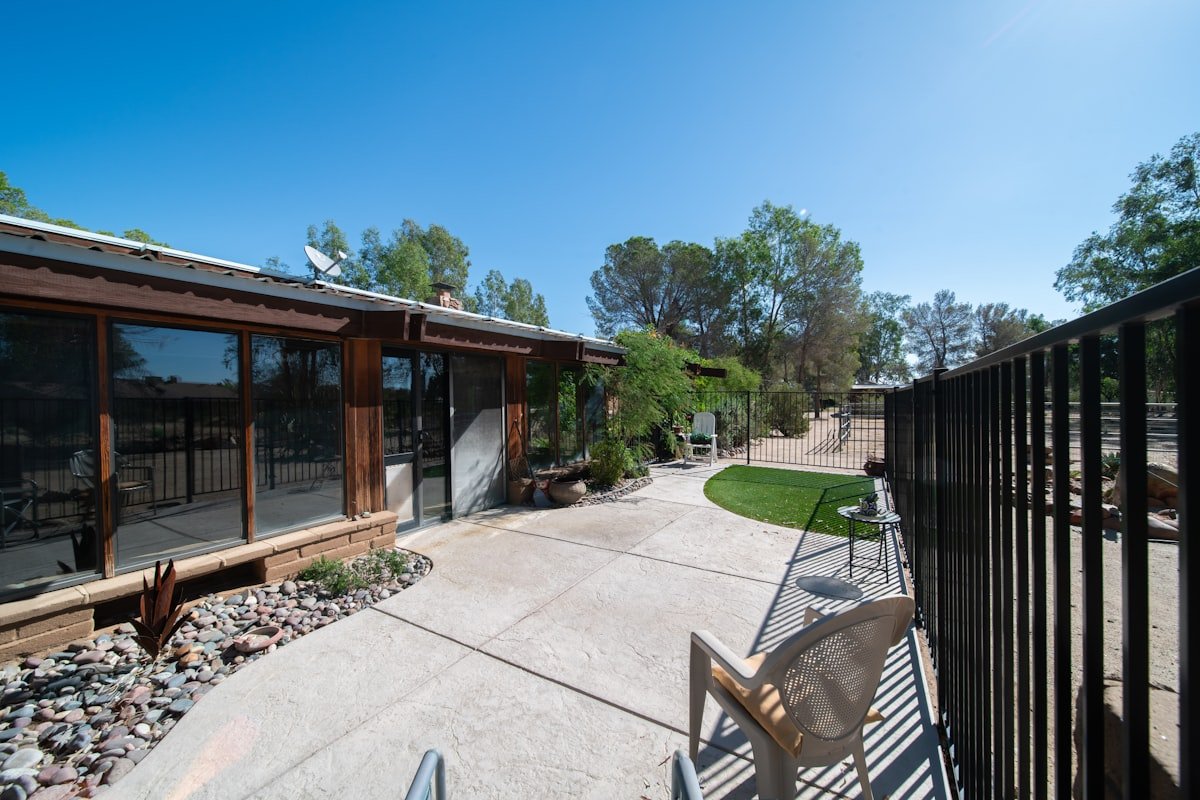 A maintained desert yard with gravel beds, a small lawn and mature shade trees